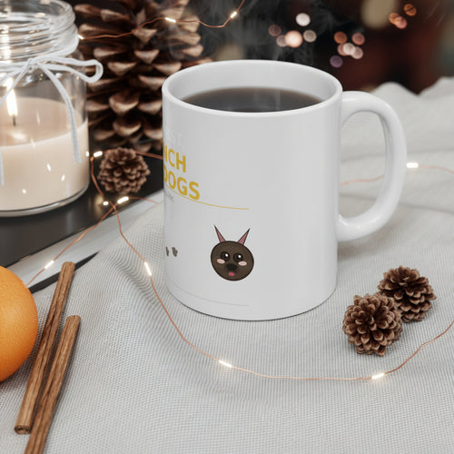 White mug with a dog illustration and text, surrounded by pine cones, an orange, and cinnamon sticks on a table.
