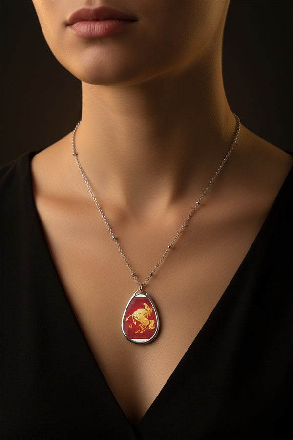 Teardrop-shaped pendant with a red background and gold horse design on a white chain.